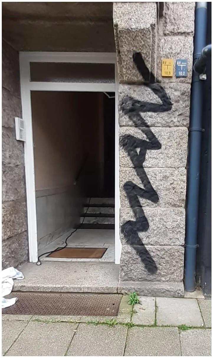 Eine Natursteinmauer, die mit schwarzem Graffiti verunreinigt ist.