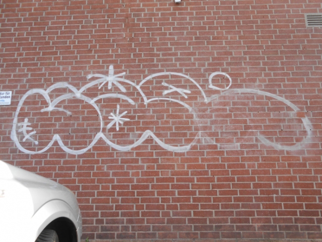 Rote Klinkermauer, beschmiert mit Graffiti, bevor der Graffitientfernung