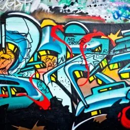 Eine Nahaufnahme einer Wand, die mit lebhaften Graffiti-Kunstwerken in verschiedenen Farben und Designs bedeckt ist.