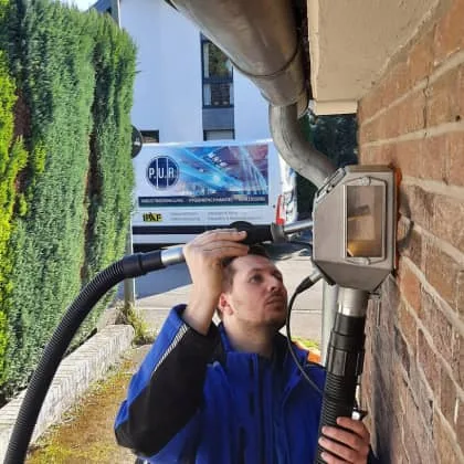 Ein PUR Mitarbeiter entfernt ein Graffiti mit dem Vakuumstrahlverfahren. Man sieht die Glocke der Reinigungsmaschine.