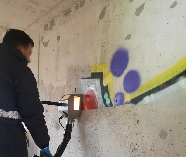 PUR-Mitarbeiter entfernt Graffiti von einer Betonwand mit dem Vakuumstrahlverfahren bei kaltem Wetter.