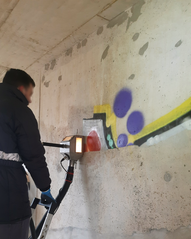 PUR-Mitarbeiter entfernt Graffiti von einer Betonwand mit dem Vakuumstrahlverfahren bei kaltem Wetter.